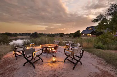 a fire pit with chairs and a table with candles at Kingfisher Villa in Mabula Game Reserve in Mabula