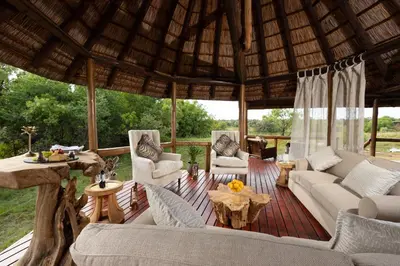 a living room with couches and chairs on a wooden deck at Kingfisher Villa in Mabula Game Reserve in Mabula