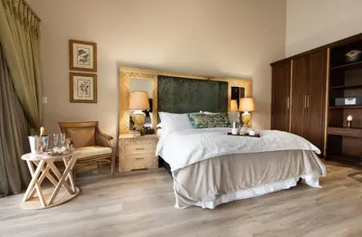 a bedroom with a large bed and a chair at Kingfisher Villa in Mabula Game Reserve in Mabula