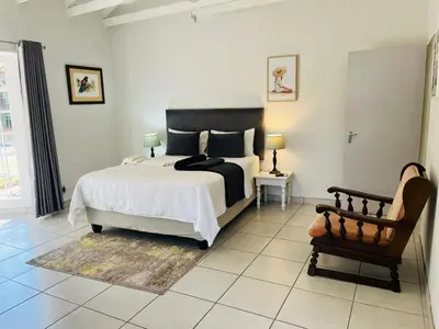 a bedroom with a large bed and a chair at WOODS GUEST HOUSE in Middelburg