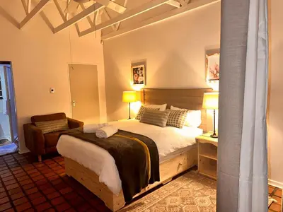 a bedroom with a large bed and a chair at WOODS GUEST HOUSE in Middelburg