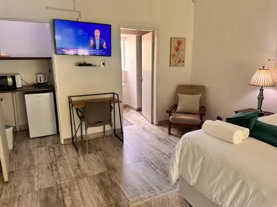 a hotel room with a bed and a television on the wall at WOODS GUEST HOUSE in Middelburg