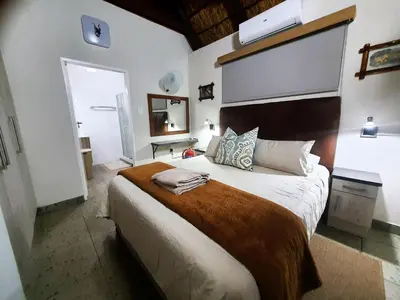 a bedroom with a large bed with a large headboard at Hippo's Honk at Kruger in Marloth Park
