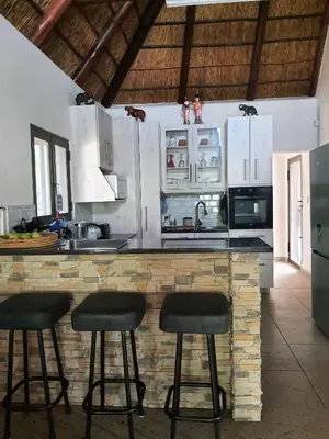 a kitchen with a counter with stools at it at Hippo's Honk at Kruger in Marloth Park