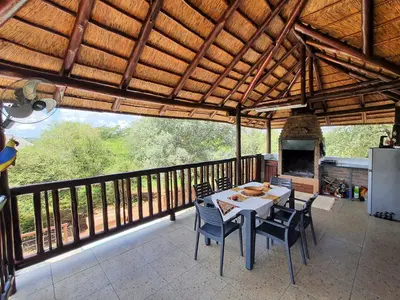 a dining room with a table and chairs on a balcony at Hippo's Honk at Kruger in Marloth Park