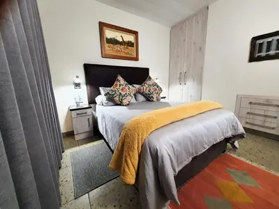 a bedroom with a bed with a orange blanket on it at Hippo's Honk at Kruger in Marloth Park