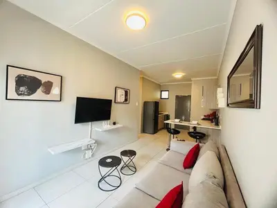 a living room with a couch and a kitchen at Mellow-Suites Apartments 130 - WIFI and Netflix in Midrand