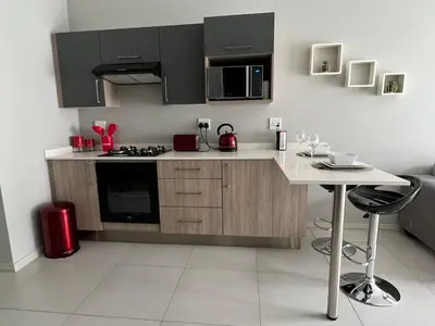 a kitchen with black cabinets and a white counter top at Mellow-Suites Apartments 130 - WIFI and Netflix in Midrand