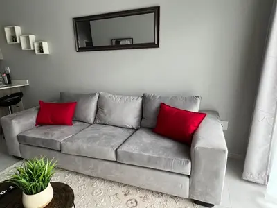 a gray couch with red pillows in a living room at Mellow-Suites Apartments 130 - WIFI and Netflix in Midrand