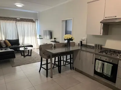a kitchen and living room with a table and a couch at Spacious 2 Bedroom Apartment in Carslwald, Midrand - Business and Family friendly - 1 Harriet Place in Midrand