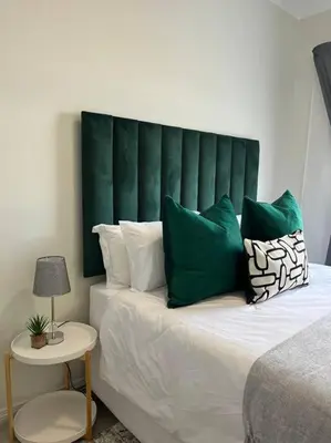 a bed with a green headboard and green pillows at Spacious 2 Bedroom Apartment in Carslwald, Midrand - Business and Family friendly - 1 Harriet Place in Midrand