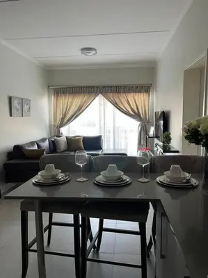 a living room with a table with plates and wine glasses at Spacious 2 Bedroom Apartment in Carslwald, Midrand - Business and Family friendly - 1 Harriet Place in Midrand