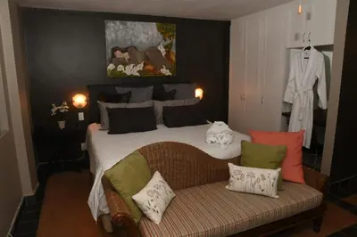 a bedroom with a bed and a couch with pillows at Tranquil Garden Nest in Nelspruit
