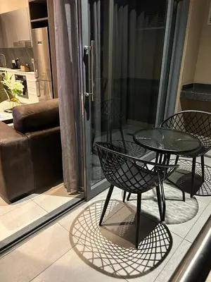a patio with a table and chairs on a balcony at Triology Menlyn Maine Residences in Pretoria