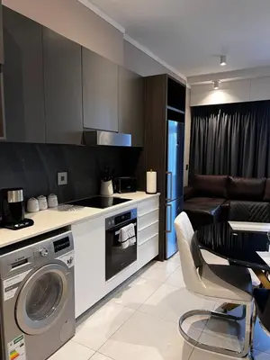 a kitchen with a washing machine and a dining room at Triology Menlyn Maine Residences in Pretoria