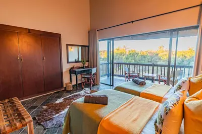 a bedroom with two beds and a balcony at Kubu Lodge in Mabula