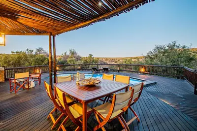 a wooden deck with a table and chairs on it at Kubu Lodge in Mabula