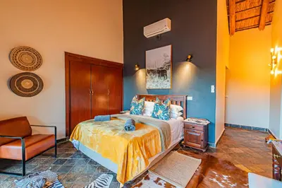 a bedroom with a bed and a chair at Kubu Lodge in Mabula