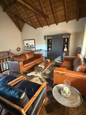 a living room with leather furniture and a table at Kubu Lodge in Mabula