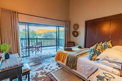 a bedroom with a bed and a balcony at Kubu Lodge in Mabula