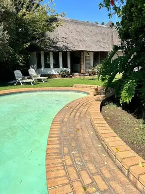 a dog sitting next to a brick walkway around a pool at SHONALANGA - Secured cottage in equestrian estate - LOADSHEDDING FREE! in Midrand