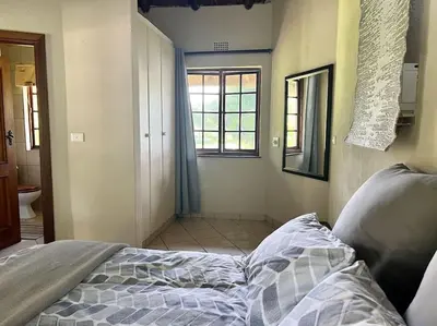 an unmade bed in a room with a window at SHONALANGA - Secured cottage in equestrian estate - LOADSHEDDING FREE! in Midrand