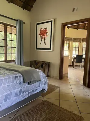 a bedroom with a bed and a living room at SHONALANGA - Secured cottage in equestrian estate - LOADSHEDDING FREE! in Midrand