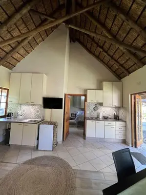 a large kitchen with white cabinets and a table at SHONALANGA - Secured cottage in equestrian estate - LOADSHEDDING FREE! in Midrand