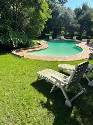 a table and a chair next to a swimming pool at SHONALANGA - Secured cottage in equestrian estate - LOADSHEDDING FREE! in Midrand
