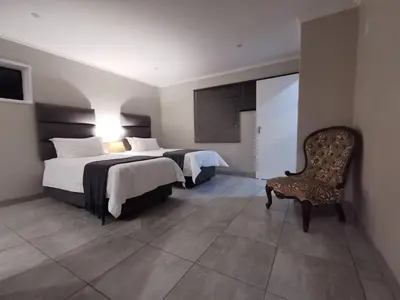 a hotel room with two beds and a chair at Stay@603 Guesthouse in Pretoria
