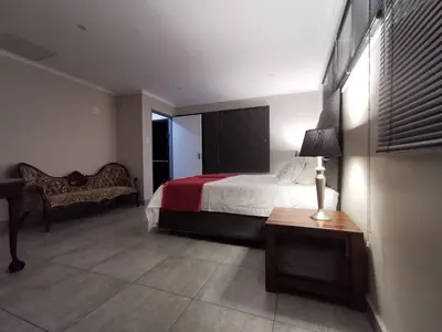 a bedroom with a bed and a table and a lamp at Stay@603 Guesthouse in Pretoria