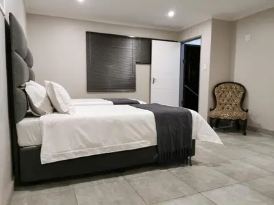 a bedroom with a large bed and a chair at Stay@603 Guesthouse in Pretoria