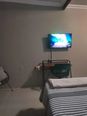 a bedroom with a bed and a tv on the wall at Comfort place 2 in Pretoria