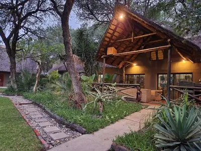 a house with a thatched roof and a pathway at Leopard Rock Guest Lodge in Mica