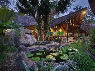 a pond in front of a house with a resort at Leopard Rock Guest Lodge in Mica