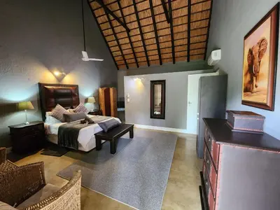 a bedroom with a bed and a table in a room at Leopard Rock Guest Lodge in Mica