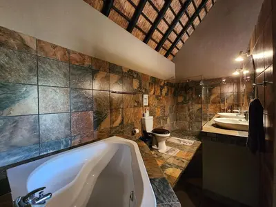 a bathroom with a tub and two sinks and a toilet at Leopard Rock Guest Lodge in Mica