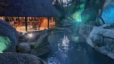 a pool of water with rocks and a building at Leopard Rock Guest Lodge in Mica