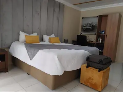 a bedroom with a large bed with a suitcase at 30 on Bergh in Louis Trichardt