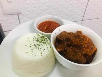 a plate of food with meat and a bowl of chili at 30 on Bergh in Louis Trichardt