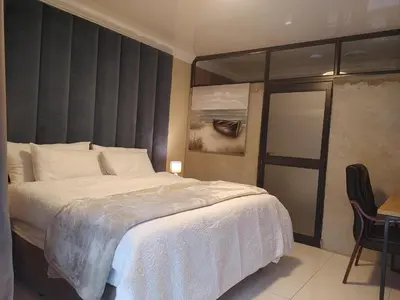 a bedroom with a large white bed and a chair at 30 on Bergh in Louis Trichardt