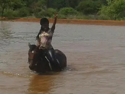 a person riding a horse in the water at Timbaktu River Cottages in Moheme