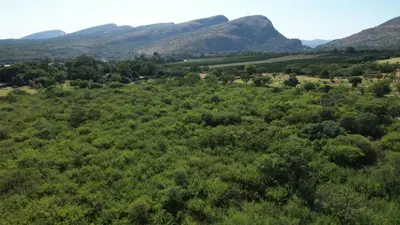 an aerial view of a field with mountains in the background at Hartbees Bush Stay #1 in Hartbeespoort