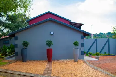 a blue building with three potted plants in front of it at Adondo-fast accommodation in Pretoria