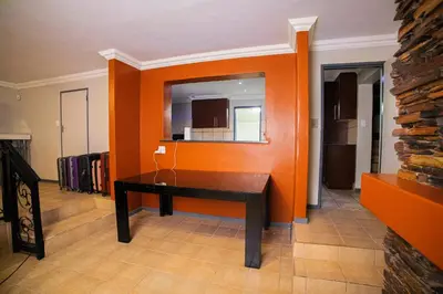 a dining room with an orange wall and a table at Adondo-fast accommodation in Pretoria