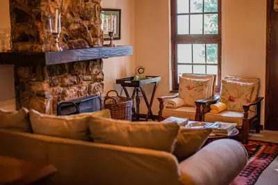a living room with couches and a stone fireplace at Crossroads Cottage in Dullstroom