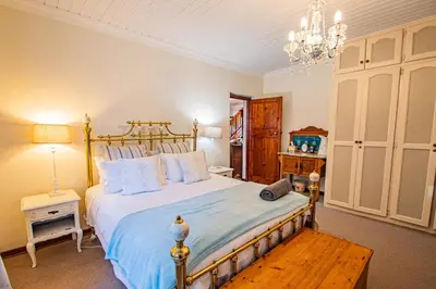 a bedroom with a large bed and a chandelier at Crossroads Cottage in Dullstroom