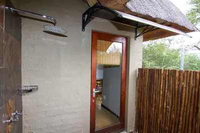 a door to a house with a thatched roof at Ingwe Bush Lodge in Hoedspruit