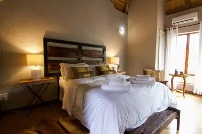 a bedroom with a large bed with white sheets and pillows at Ingwe Bush Lodge in Hoedspruit
