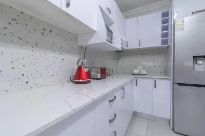 a kitchen with white cabinets and a red appliance on the counter at Greencroft Villa in Kempton Park